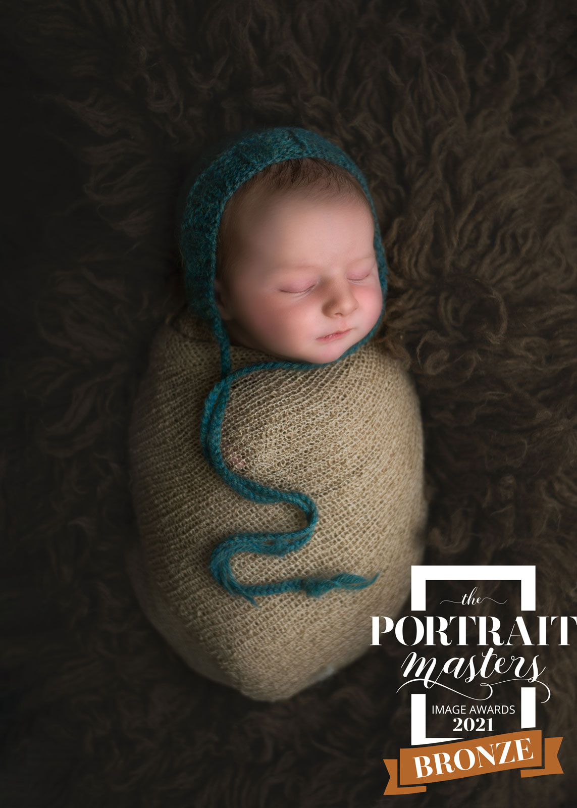 newborn with teal hat and tan wrap