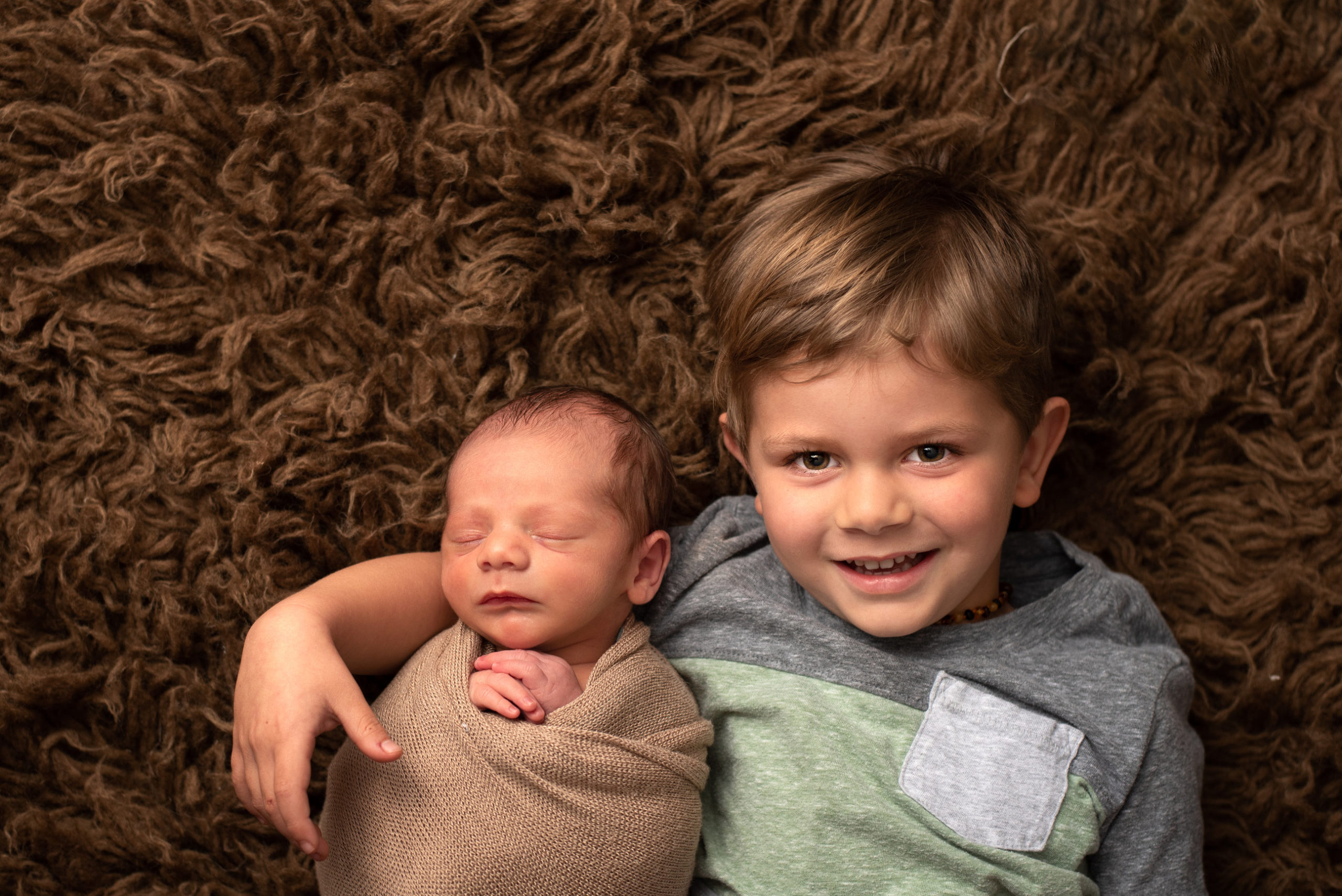 How long does a newborn photo session take? Newborn baby and sibling on flokati