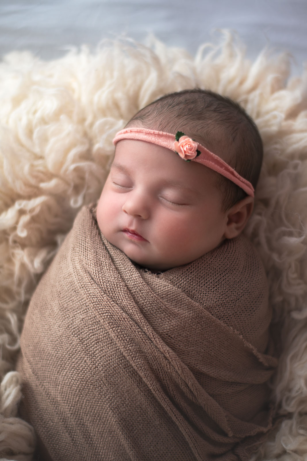 baby girl in pink headband and neutral wrap at newborn photo session
