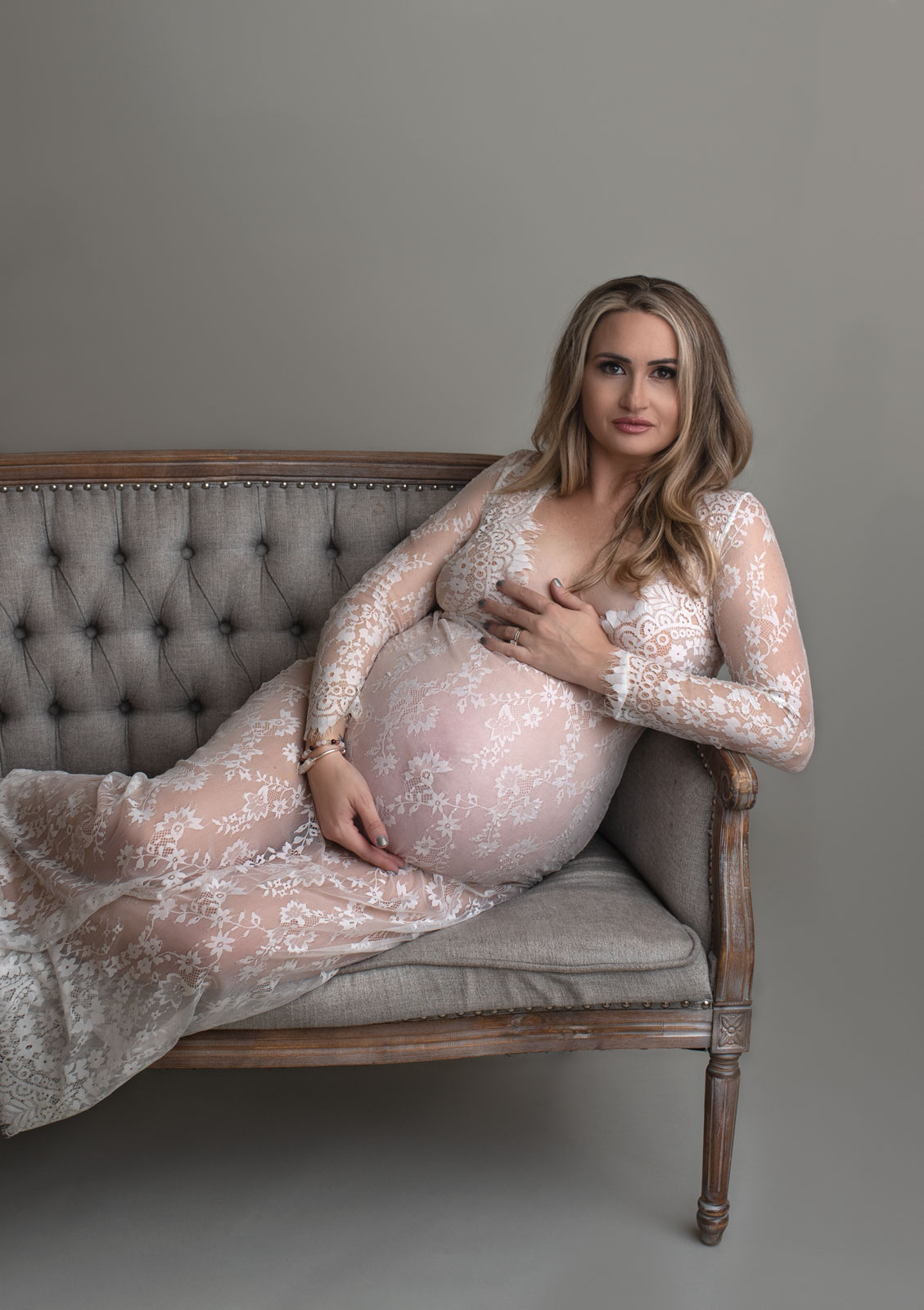pregnant woman in lace dress posing on sofa