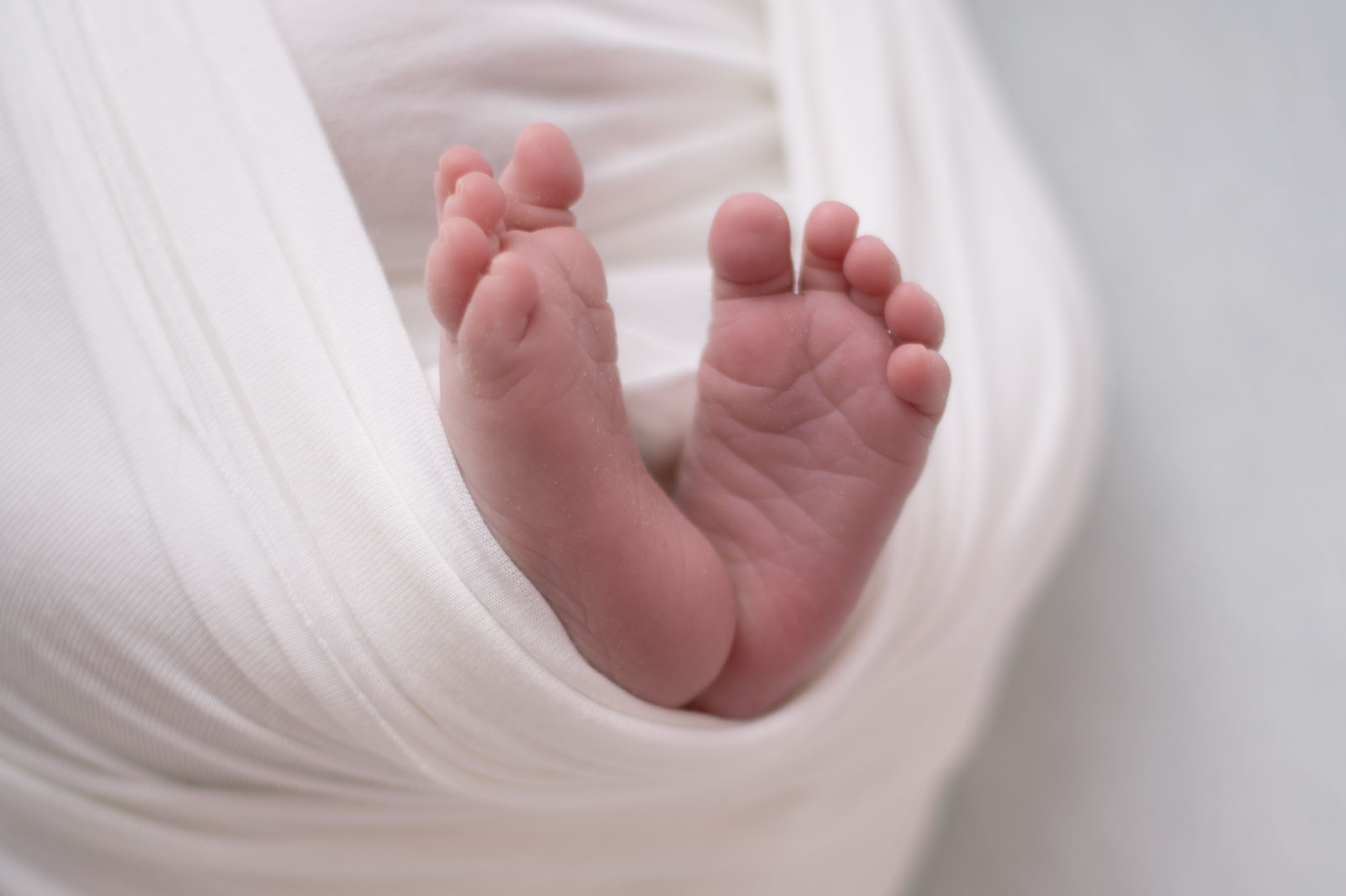 detail of baby feet wrapped in a white cloth