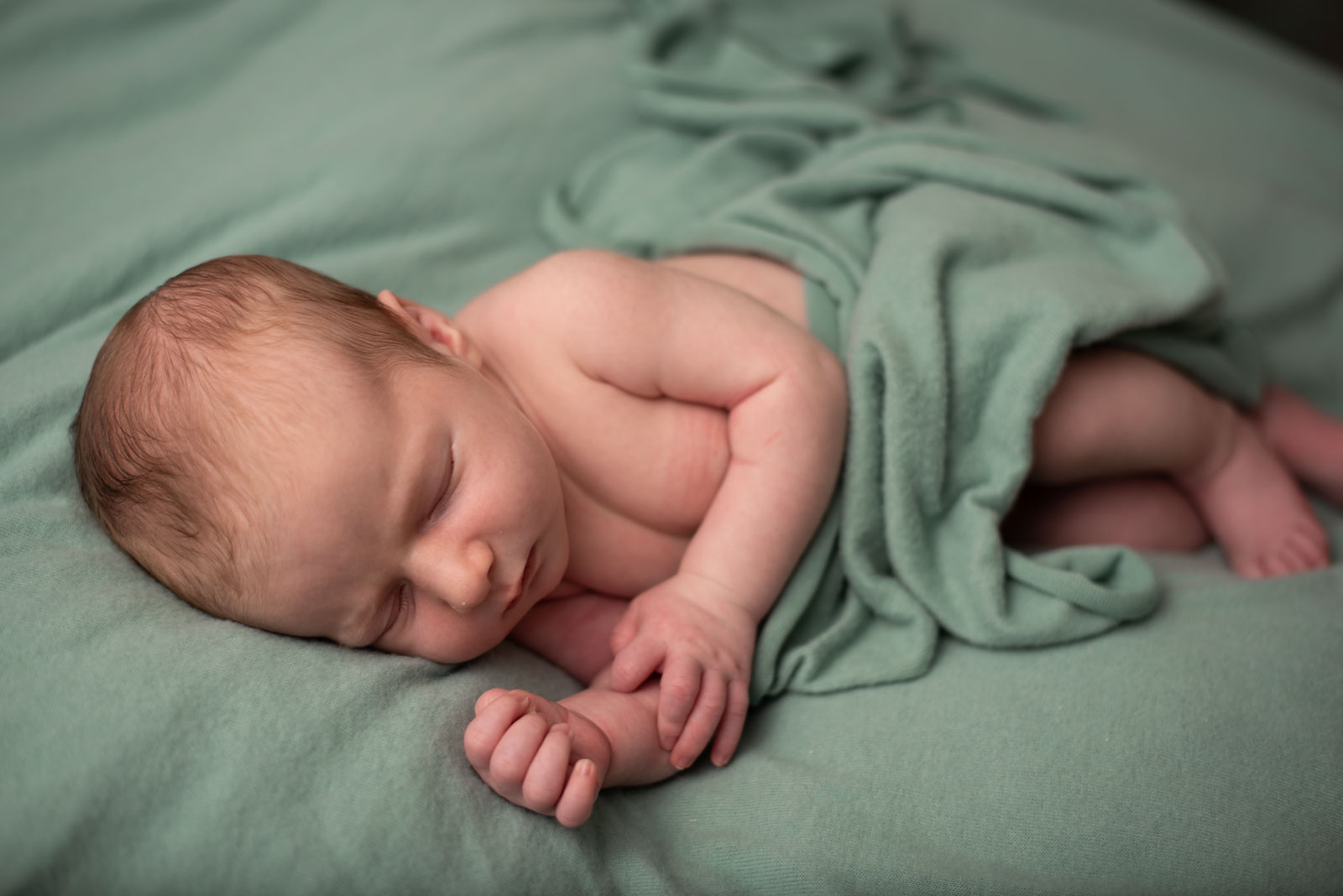 newborn baby laying on a green blanket and wrapped in a green cloth 3 St. Louis Baby Stores with Trendy & Affordable Kid's Products