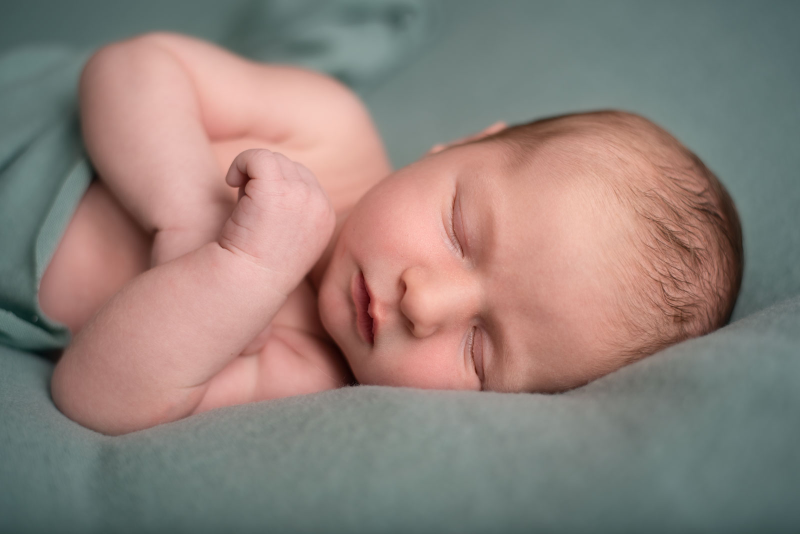 newborn baby sleeping on a green cloth with arms crossed 3 St. Louis Baby Stores with Trendy & Affordable Kid's Products