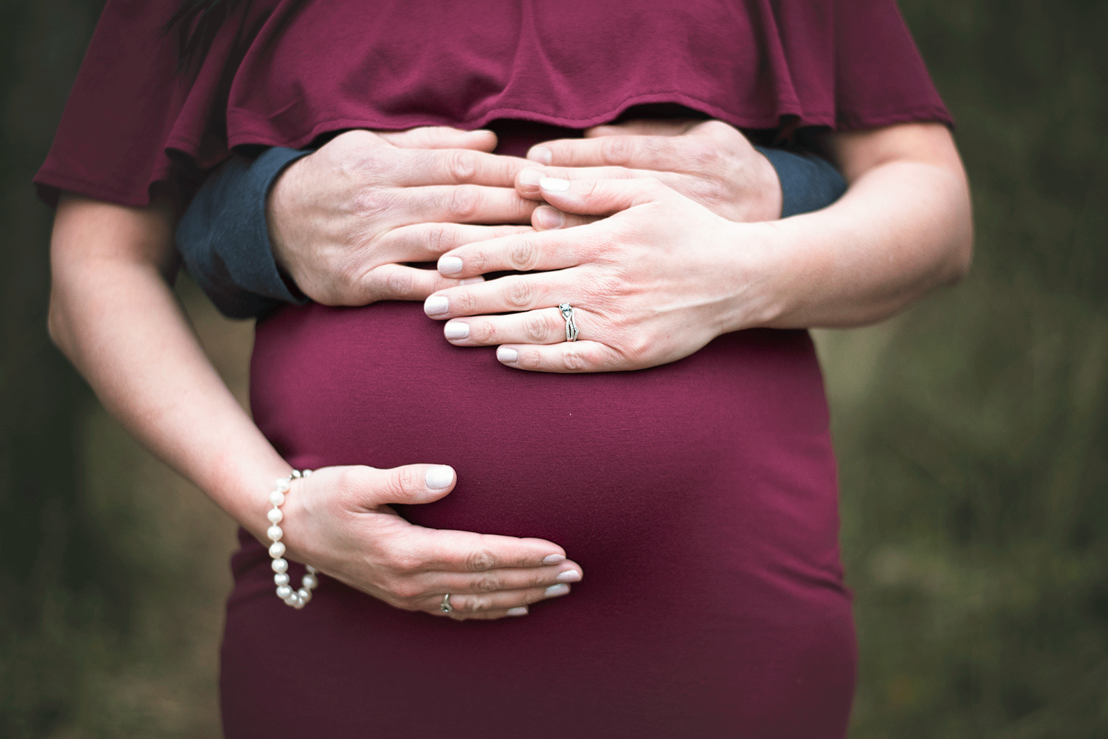 hands of a mother and father on a baby bump st louis birthing center