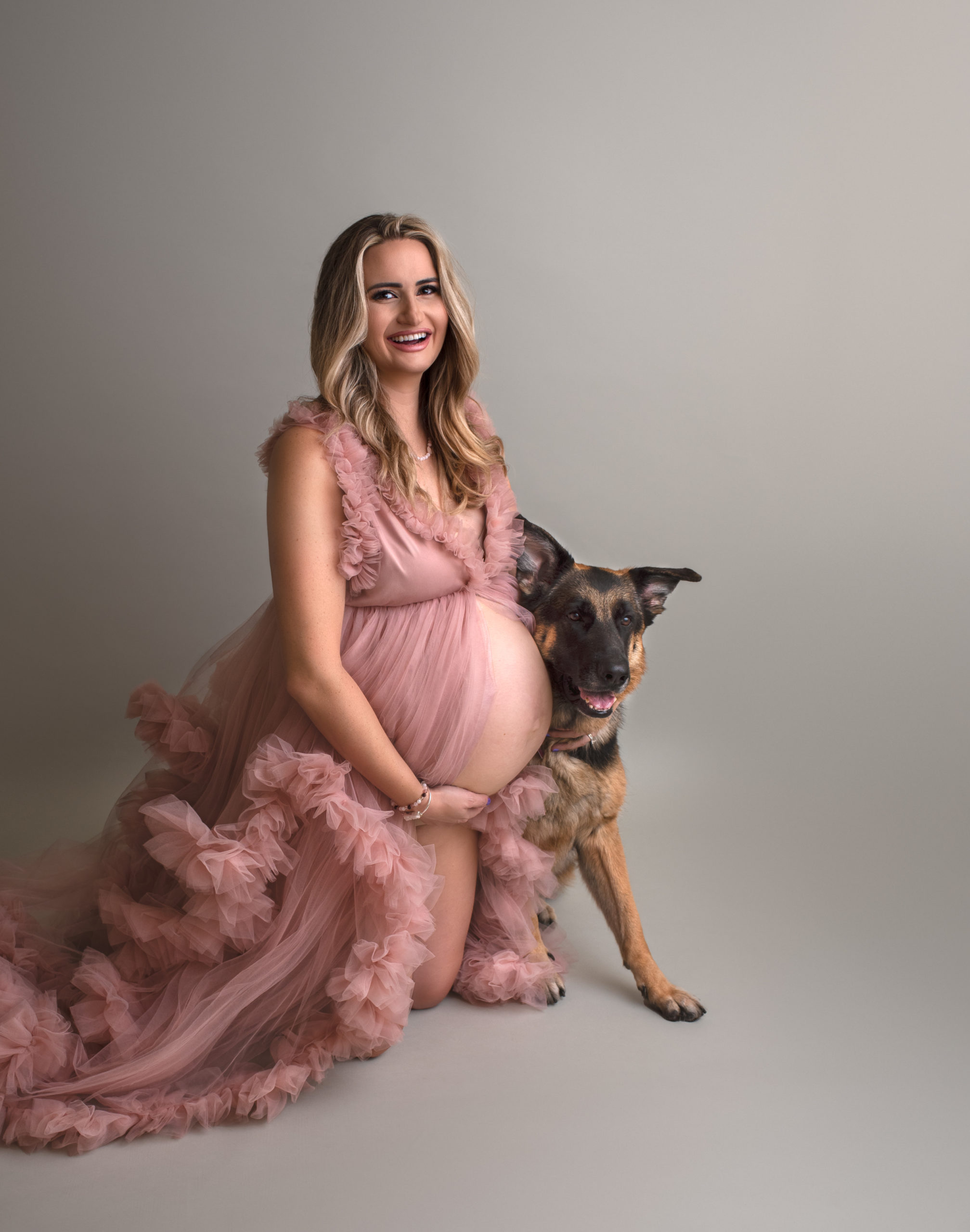 mom to be in pink maternity gown sitting with her dog St. Louis Prenatal Yoga
