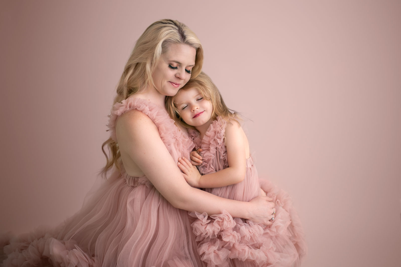 mom to be in a pink maternity gown holding her young child