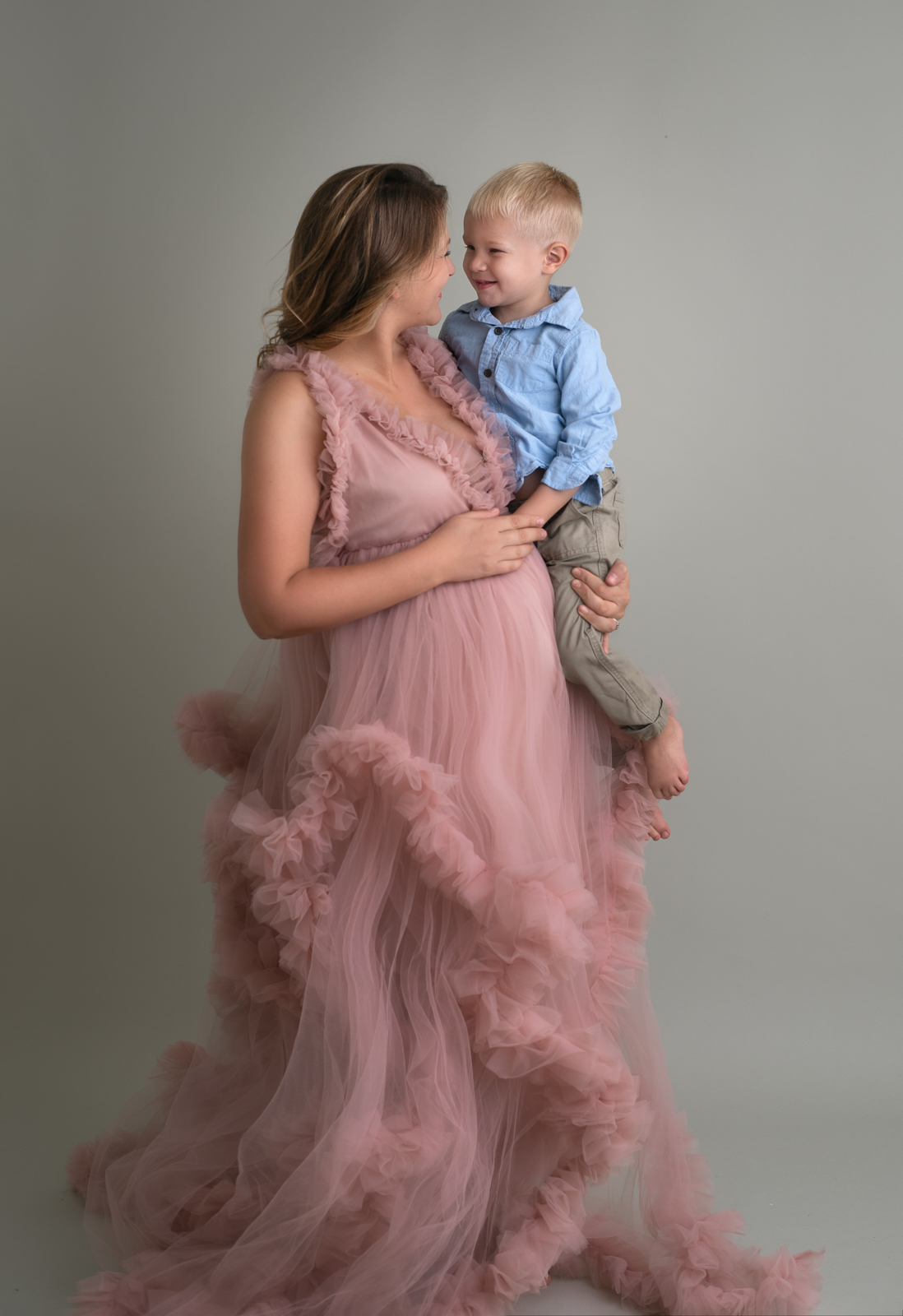 mom to be in a pink tulle gown holding her young son daycare st louis